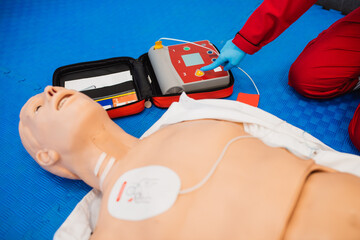 Cpr with aed training. Paramedic demonstrate Cardiopulmonary resuscitation (CPR) on dumm and holds his finger on the apparatus - obrazy, fototapety, plakaty