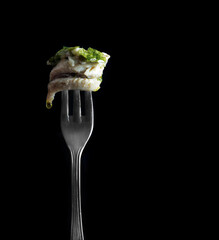 Anchovies marinated in vinegar with olive oil and parsley on fork. Fine Spanish food.
