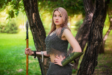 Portrait of a young medieval woman warrior dressed in chain mail armor with a spear in her hands on...