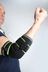 close-up of a man's elbow, part of a European's hand in a black elastic bandage, elastic roller Compression bandage concept of fixing an injured limb