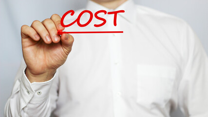 A businessman in a white shirt writes a text COST on a white background with a red marker . business concept