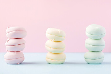Three piles of colorful marshmallows on pastel pink and blue background. Balance concept. Sweets and confectionery in stacks on bright backdrop.