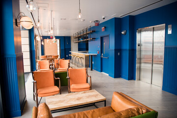 Modern interior dining and meeting space with burnt orange chairs and deep blue walls with hipster lights hanging