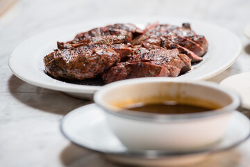 Grilled medium steak slices with a side of soy sauce.