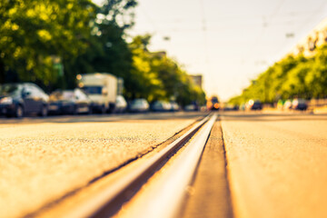 Sunny day in a city, tram rides on rails, view from the level of asphalt