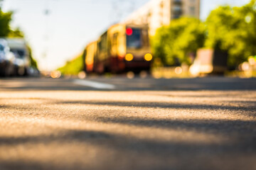 Sunny day in a city, tram rides on rails, view from the level of asphalt