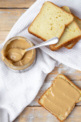 Peanut butter on white bread on wooden background. Flat lay