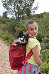 jeune fille pratiquant la randonnée avec un chiwuawua dans son sac à dos