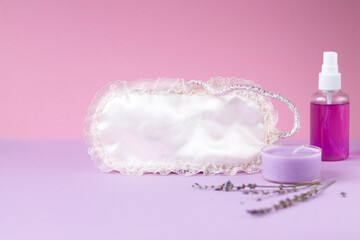 Obraz na płótnie Canvas Eye mask for sleeping, lavender candle, lavender oil on a pink background. The concept of restful sleep. Space for text