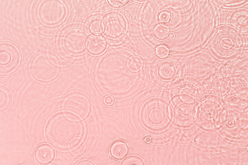 Pink transparent clear calm water surface texture with ripples, splashes and bubbles Abstract summer nature background Coral colored waves in sunlight Cosmetic moisturizer micellar toner emulsion