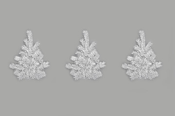 Festive composition with three Christmas trees made of natural fluffy white fir branches on gray background. Trendy monochrome xmas template. Top view, flat lay style, copy space for text