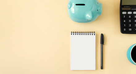 Planning concept with notepad, piggy bank, calculator and coffee. Banner of yellow pastel color with copy space