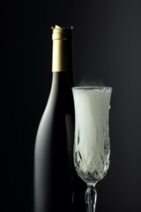 Bottle and glass of champagne on a black background.