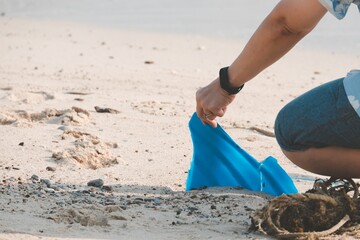 Woman picking up trash and plastics cleaning the beach, tropical beach vacation