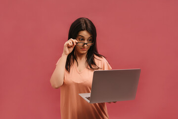 Image of a surprised screaming optimistic emotional young woman posing isolated over pink wall background dressed in pink casual t-shirt using laptop computer.