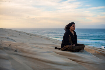 Woman sitting on sand dune at the beach