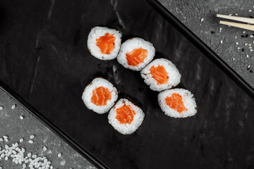 Simple maki with fresh salmon. Sushi on a gray background