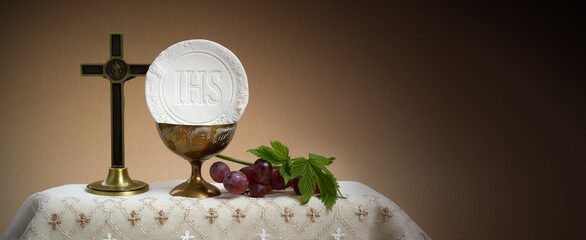 The Feast of Corpus Christi Concept. Holy communion and cup of glass with red wine on table.