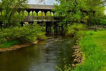 Covered wooden foot bridge over small peaceful creek in Reed City, Michigan.