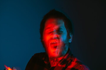 Conceptual portrait, with movement and out of focus of a tattooed person screaming with a gesture of agony and madness. mind States. Anxiety.