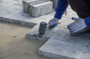 Construction of pavement near the house. Bricklayer places concrete paving stone blocks for building up a Sidewalk pavement