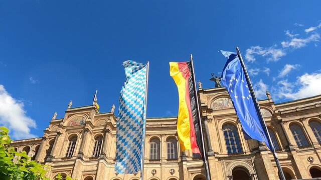 Bavarian, German and European Union flags flying in the wind in front of the Maximilianeum / Bavarian State Parliament building in Munich, Germany