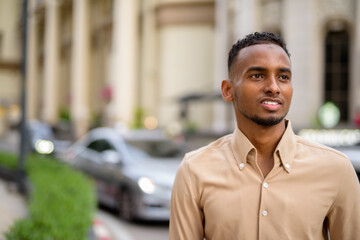 African businessman smiling and thinking outdoors in city