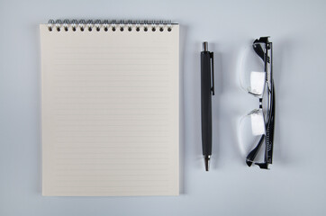 Notebook pen and glasses, white background.