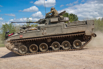 Fototapeta na wymiar british army FV510 Warrior light infantry fighting vehicle tank kicking up dirt in action on a military exercise Wiltshire UK