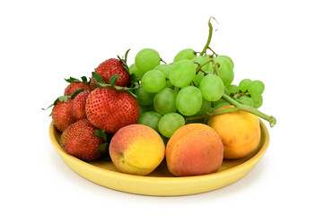 Naklejka na ściany i meble Fruits and berries are on a wooden plate. Apricots, strawberries and green grapes