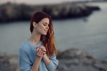 red-haired woman in a blue sweater near the river in nature
