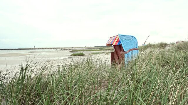 4K moving video of beach chair on white sand and dunes at cloudy weather at Baltic sea in north Germany