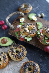 Bagels with salmon, avocado and green lettuce on a wooden board. Breakfast with light healthy snacks.