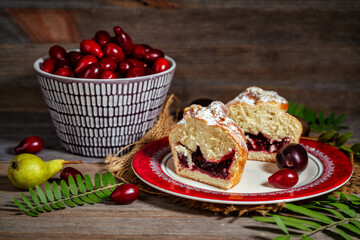 Muffin sprinkled with powdered sugar and a bowl of dogwood on a wooden table