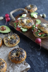 Bagels with salmon, avocado and green lettuce on a wooden board. Breakfast with light healthy snacks.