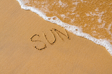 Inscription sun on the sandy shore eroded sea wave