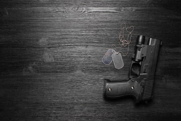 Black airsoft gun and soldier badge on the black flat lay background with copy space.