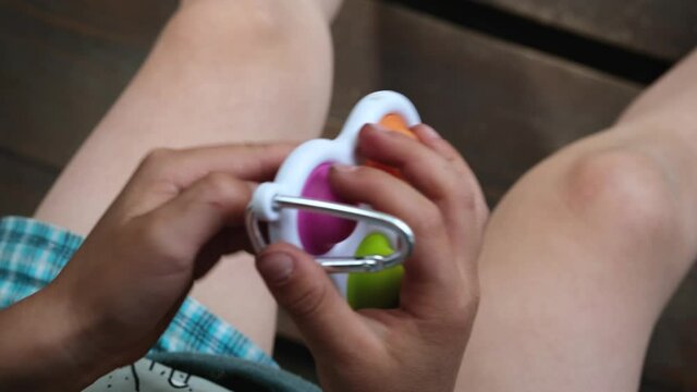 Child playing with antistress simple dimple fidget toy. Kid holding trendy silicone pressure relieving sensory pop it toy.