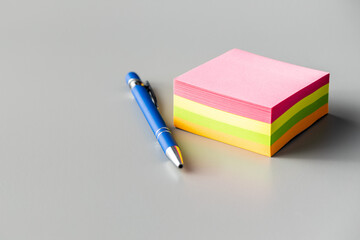 Blank sticky paper notepad and pen on gray table.