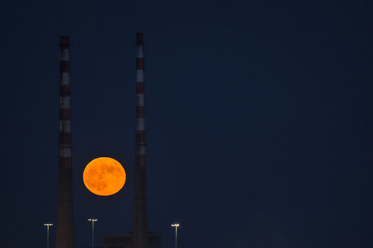 Beautiful View Of Red Super Flower Moon Rise In The Irish Sky Between Iconic Poolbeg Generating Station (Poolbeg CCGT) Chimneys On May 26, 2021 Seen From Dublin City Motocross Track, Dublin, Ireland