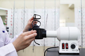 Optical workshop and salon. Eyeglass repair. Straightening the frame of glasses with a Optical hair dryer