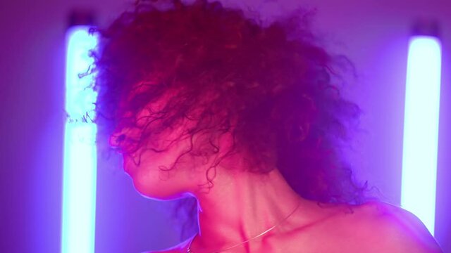 Cool disco dancing unique afro woman under neon glowing light. Multi colored shot of lady moving to music rhythm. Millennial hipster generation. Party concept.