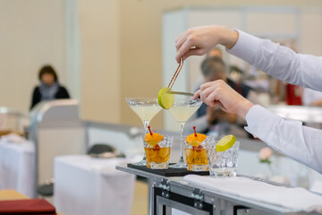 Professional man bartender hands making alcoholic cocktail on bar counter - close up