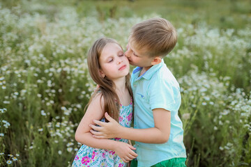 A blonde boy with a blonde girl in a chamomile field