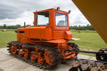 Obraz na płótnie Canvas Old red tracked tractor standing near field