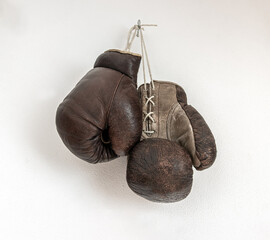 Old boxing gloves hanging on a white wall
