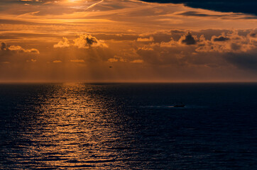Sunset through clouds over a calm sea