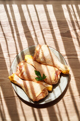 Vertical composition of the top view of a plate with raw chicken legs on a wooden table next to a...