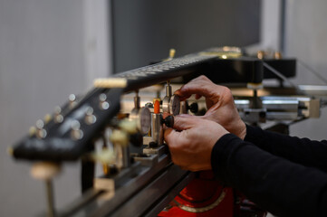 Electrical guitar in repair service shop with a hands of a guitar luthier