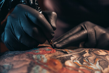 Hands of a tattoo artist wearing black gloves and holding a machine - Powered by Adobe